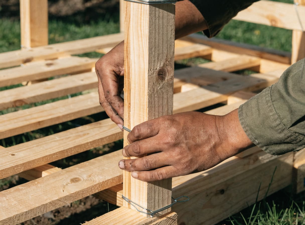 Three wooden pallets wired together in a U-shape to form a DIY compost bin frame