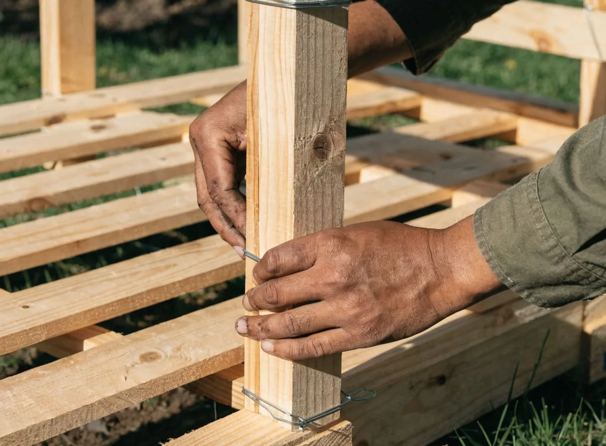 Three wooden pallets wired together in a U-shape to form a DIY compost bin frame