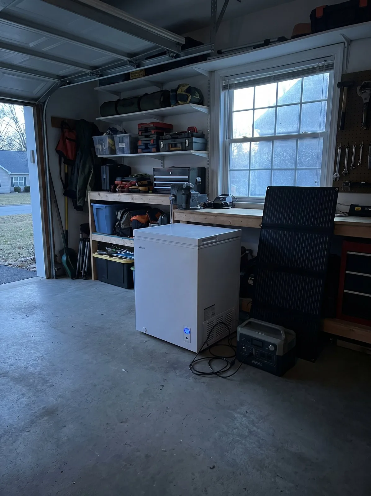 A chest freezer in a garage running off a portable power station and a small folding solar panel